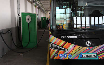 Vorderansicht Bus vor drei Ladestationen in der Fahrzeughalle