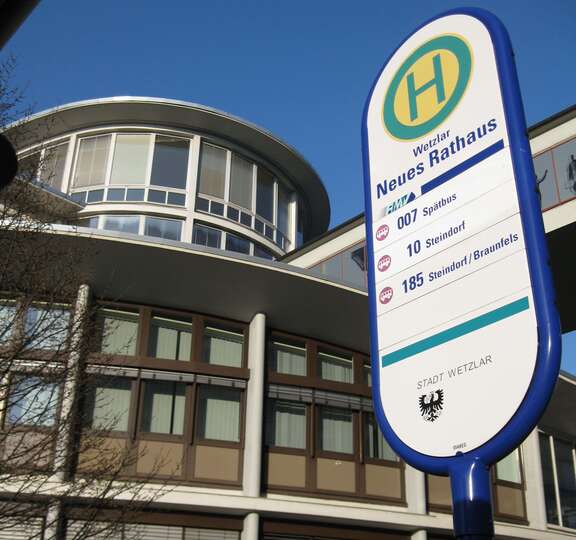 Neues Rathaus Wetzlar Das Bild zeigt das Haltestellenschild der Bushaltestelle "Neues Rathaus" vor der Ansicht der prächtigen Rathausfassade (ehemaliges Verwaltungsgebäude der Firma Leitz aus den Fünfziger Jahren) und darüber einen strahlend blauen Himmel.