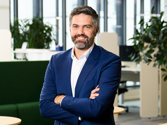 Ein Mann in einem blauen Anzug sitzt in einer Bürolandschaft.