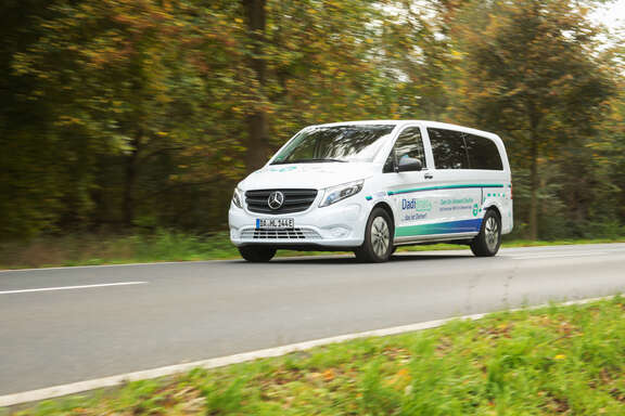 Ein weißes großes Auto fährt auf einer Straße im Grünen