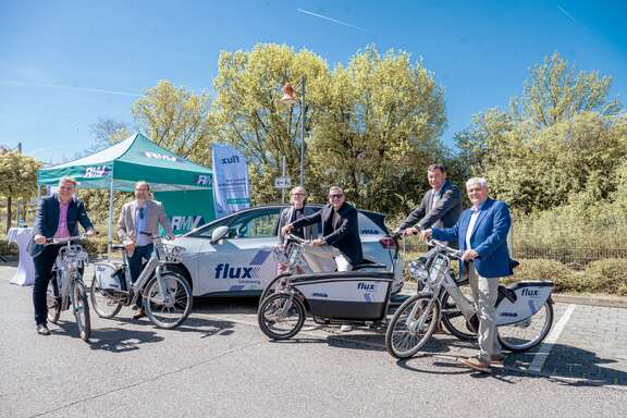 Politiker und RMV-Vorstand mit E-Fahrrädern und Elektroautos vom Sharing-Anbieter flux.