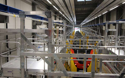 Ein rot-gelber Zug steht in einer Werkstatt, daneben viele hellgraue Gänge.