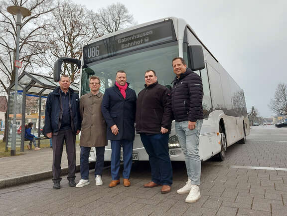 Mehrere Männer stehen vor einem Bus.