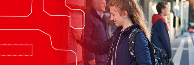 Teaserbild: Eine junge Frau steht an einer Bushaltestelle und tippt auf einen Fahrplan an einem digitalen Display. Im Hintergrund warten weitere Personen, und ein Bus ist in der Ferne zu sehen. Links ist der Bildbereich grafisch in Rot mit weißen Linien gestaltet.