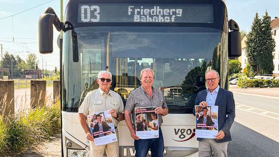 Richter, Weber und Hofmann mit den Plakaten vor einem Stadtbus in Friedberg