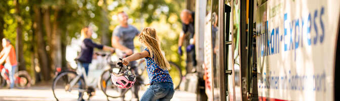 Mädchen steigt aus dem Bus und läuft in Richtung Fahrradanhänger