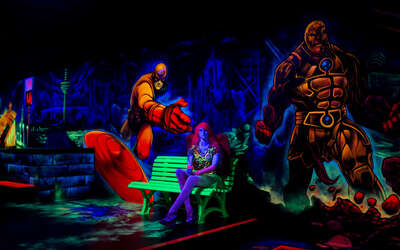 Vergrößerte Ansicht: Frau sitzt auf einer Bank vor einer leuchtenden Wand, alles leuchtet in Neonfarben