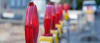 Das Bild zeigt Absperrschranken mit roten Lampen einer Straßenbaustelle.