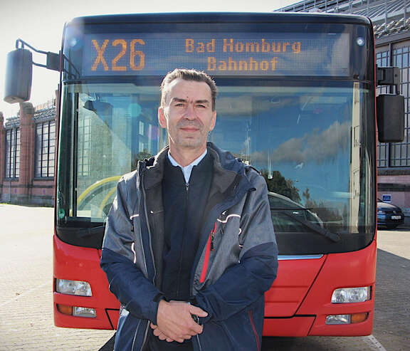 Ein Mann steht vor einem Bus.