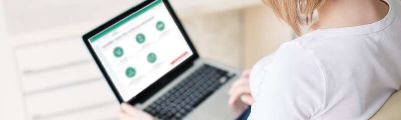 Frau sitzt am Laptop und meldet sich bei meinRMV an