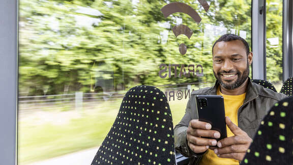 Mann mit Handy im Zug.