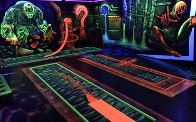 Vergrößerte Ansicht: Raum mit mehreren Golfbahnen mit Loopings und bunten Motiven an den Wänden