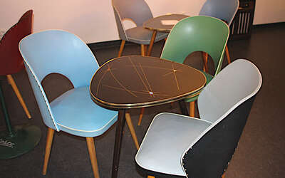 Blauer, grüner und hellgrauer Cocktailsessel um ein Nierentisch