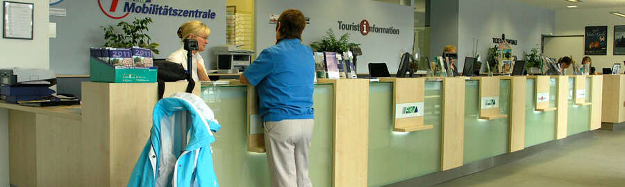 eine Frau mit Koffer am Schalter einer RMV-MobilitätsZentrale