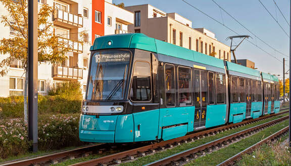 Eine mintgrüne Straßenbahn vor Wohnhäusern