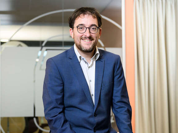 Ein Mann in einem blauen Anzug sitzt in einer Bürolandschaft.