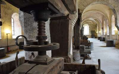 Altes Holzgerät zum Keltern von Wein in einem langen Raum.