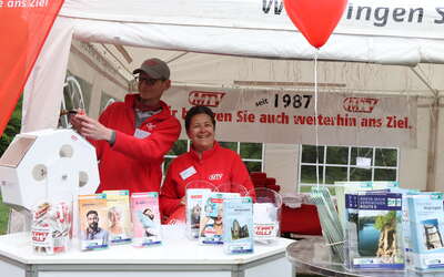 Zwei MTV-Mitarbeiter stehen im Pavillon. RMV- und MTV-Flyer stehen zur Vergabe bereit.