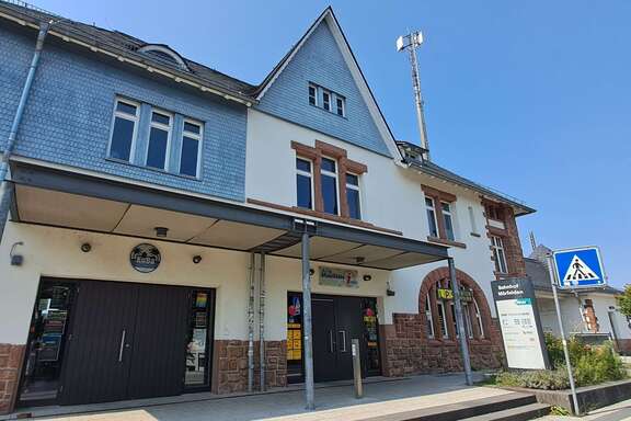Ein altes Gebäude mit einem Aufsteller davor, Schrift: Bahnhof Mörfelden