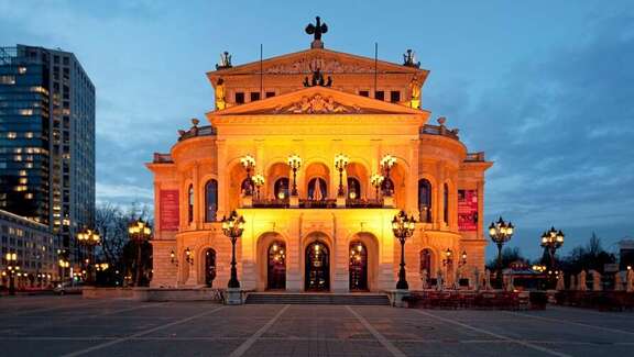 Klassizistisches Gebäude auf einem Platz, am Abend beleuchtet