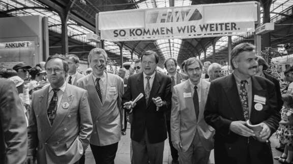 Schwarz-weiß-Foto im Frankfurter Hauptbahnhof mit Hans Eichel, Ministerpräsident des Landes Hessen (1991-1999), Lothar Klemm, Hessischer Verkehrsminister (1994-1999), Achim Exner, Oberbürgermeister der Stadt Wiesbaden (1985-1997), Jochen Riebel, Landrat des Main-Taunus-Kreises (1990-1999) und Volker Sparmann, RMV-Geschäftsführer (1995-2009).