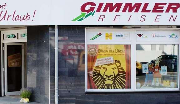 Das Bild zeigt die Schaufensterfront der RMV-Mobibilitäts-Info der Gimmler Wetzlarer Verkehrsbetriebe in der Bannstraße in Wetzlar. Es handelt sich um eine typische Geschäftsfassade in der Innenstadt.