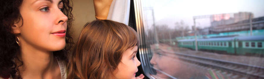 Frau und Kind auf dem Schoß schauen aus dem Zugfenster