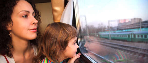 Frau und Kind auf dem Schoß schauen aus dem Zugfenster