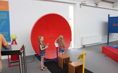 Vergrößerte Ansicht: Roter Parabolspiegel, davor zwei Mädchen