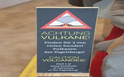 Warnschild mit Aufschrift: Achtung 3 Vulkane. Finden Sie 3 von 100 Vulkanen des Vogelbergs!