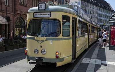 Eine gelbe Tram steht an einer Haltestelle.
