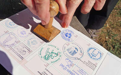 Vergrößerte Ansicht: Im Ausweis sind unterschiedliche Stempelabdrücke zu sehen, die Wanderer nach erreichten Etappen erhalten