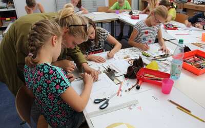 Vergrößerte Ansicht: Gruppe von Kindern an Mal-Tischen