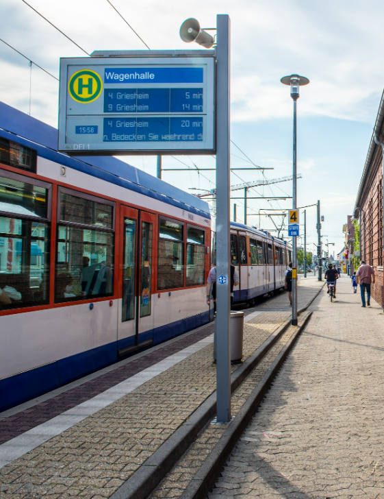 An einer Haltestelle (Schrift: Wagenhalle) steht eine Straßenbahn